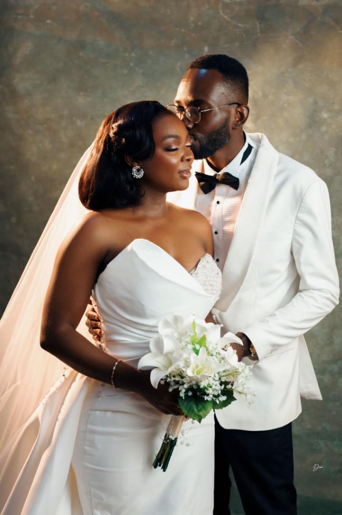 Wedding couple — bride in a white gown holding a bouquet, groom in a white tuxedo