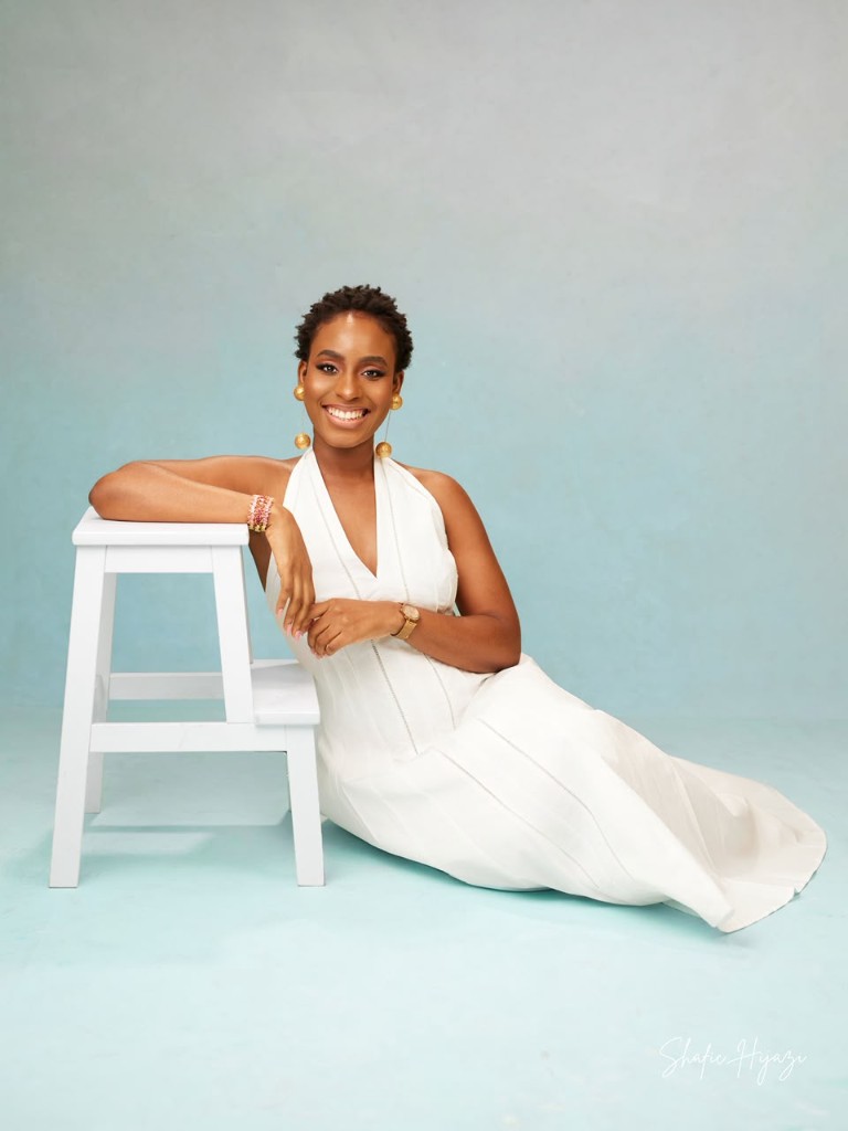 Portrait in a white halter dress against a blue backdrop