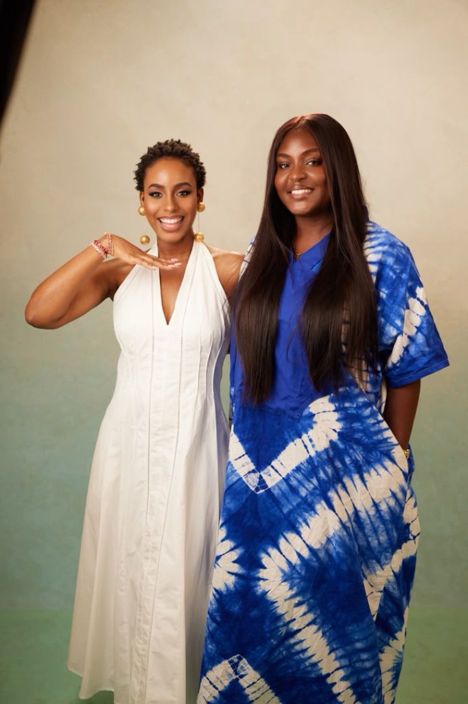 Two women posing together in white and blue studio looks